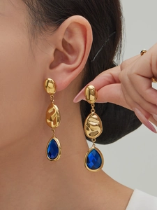 Close-up of model wearing three-tier gold waterdrop earrings with faceted blue glass stone