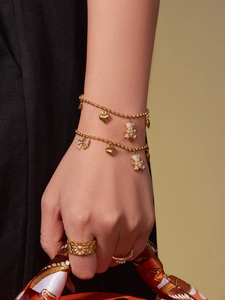 Detail of 18K gold beaded bracelet with bear heart charms and vintage sunflower ring