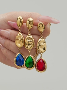Detailed macro view of 18k gold earrings featuring layered metal and pear-cut colored stones