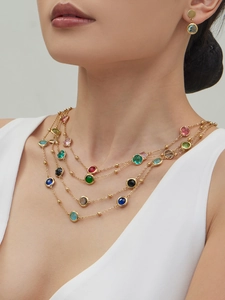 Macro detail of multi-layered gold necklace with colorful round stones on model