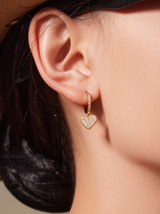 Detailed view of heart-shaped earrings with gold plating and sparkling zircon stones