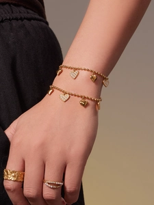 Detail of 18k gold plated double layer heart charm bracelet and pearl ring on model hand