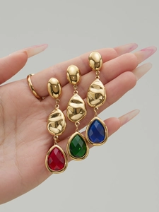 Detailed macro view of pear-shaped faceted glass stone earrings in red, green and blue colors