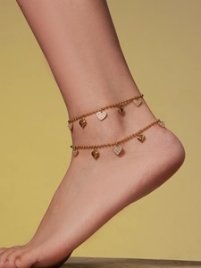 Detailed view of a double-layered gold heart anklet worn on the ankle for women