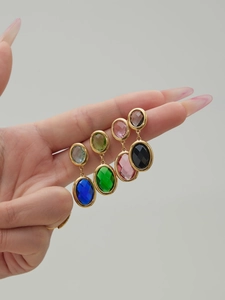 Detailed close-up of geometric oval cut glass earrings in four vibrant colors with gold plating