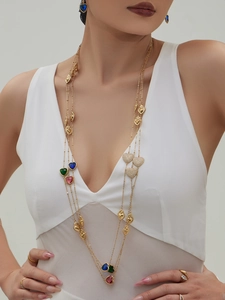 Detalle de collares de corazones dorados a capas con gemas de colores en una modelo
