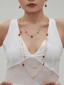 Detail of layered gold clover necklaces with faceted ruby and pink gemstones on model