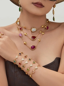Close-up of model wearing gold 18k heart bracelet and colorful resin layering necklaces