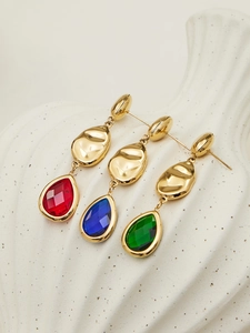 Detailed shot of gold earrings with drop-shaped red, blue, and green gemstones
