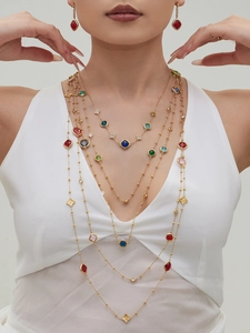 Close-up of multilayered gold necklace set with colorful gemstones and clover motifs