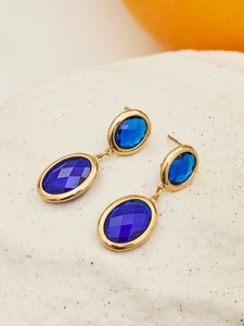 Detail of vintage gold-plated drop earrings with faceted deep blue oval crystals