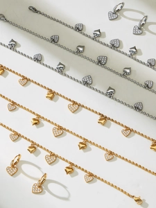 Detailed view of heart pendants in polished gold and pavé zircon on steel necklaces