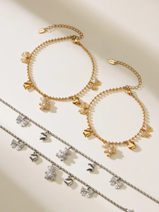 Detail of stainless steel bracelets with rhinestone bear, bow, and heart charms in gold and silver