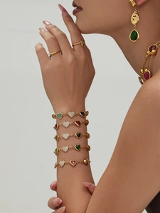 Detailed shot of gold heart bracelet set with vibrant colorful gemstones on model