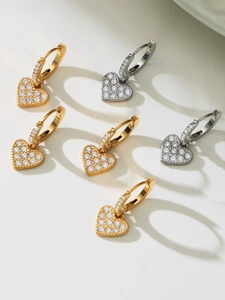 Macro detail of heart-shaped earrings with micro-paved zircons in gold and silver plating