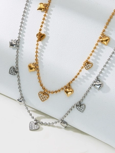 Macro shot of 18k gold bead necklace featuring multiple polished and zircon heart charms