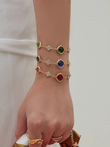 Detailed shot of gold clover bracelets with colorful faceted stones on a model's wrist