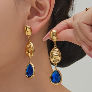 Three-tier gold teardrop earrings with blue faceted glass stones on a female model
