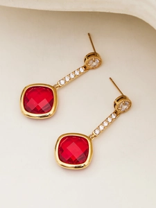 Detail of red square gemstone earrings with gold drop chain and cubic zirconia accents