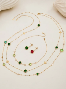 Detail of luxury jewelry set with green and burgundy gems and clover micro-inlay