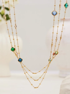 Detailed view of long gold bead necklace with vibrant multi-colored faceted gemstones