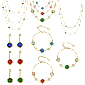 Gold clover jewelry set featuring faceted colorful gemstones and zircons on white background