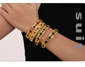 Detalle de pulseras apiladas de acero inoxidable dorado PVD con circones cuadrados de colores
