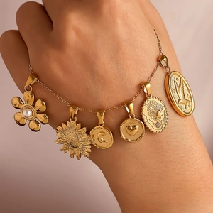 Golden bracelet with multiple charms like flower, moon, and heart on a female hand