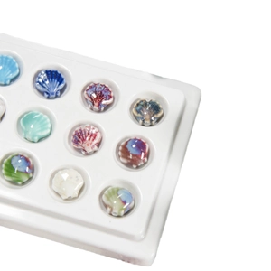 Assorted colorful ceramic shell beads for DIY jewelry making on white display tray