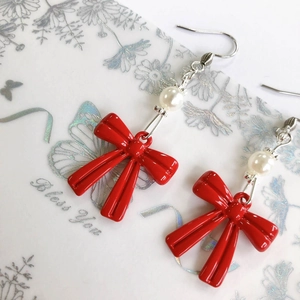 Detalle de pendientes de lazo rojo con perla blanca y acabado brillante para joyería