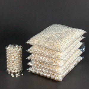 Macro detail of creamy white ABS imitation pearls in a glass jar with bulk packaging