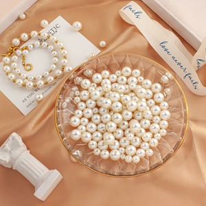 Detailed macro view of white ABS imitation pearls with golden OT clasps on silk