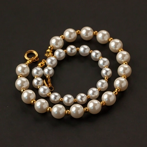 Polished white acrylic pearls and gold metal spacer beads on a matte black surface