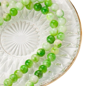 Natural green prehnite stone beads on a vintage glass plate for DIY jewelry making