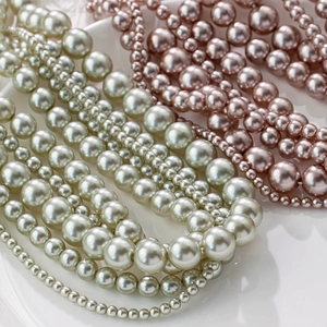Primer plano de perlas redondas de cristal en verde menta y rosa para joyería artesanal