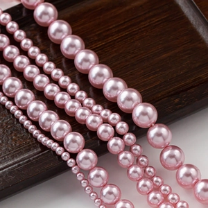 Vista macro de perlas redondas rosas en bandeja de madera mostrando varios tamaños