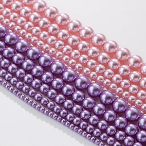 Detalle de cuentas de perlas redondas rosa y violeta en varios tamaños para bisutería
