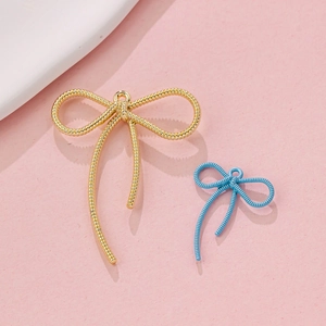Macro shot of macaron blue and gold alloy bow pendants with spiral texture for DIY jewelry