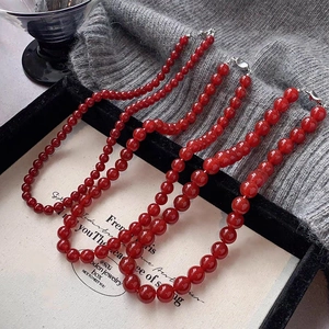 Three rows of glossy red glass beads with gold clasps in a vintage jewelry arrangement