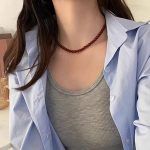 Close-up of 8mm deep red glass beads on a minimalist necklace worn by a model