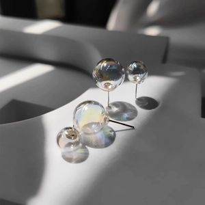 Macro detail of iridescent glass bubble stud earrings with shimmering rainbow finish