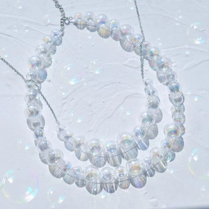 Macro detail of iridescent glass bubble pendant necklaces with shiny aurora finish