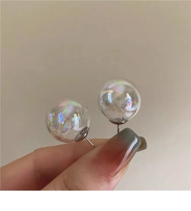 Macro view of colorful iridescent glass bubble stud earrings with aurora finish effect