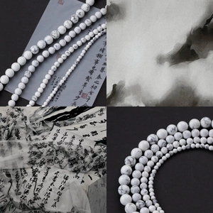 Macro shot of white howlite round beads in four sizes with natural marble veins for DIY