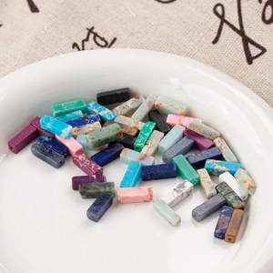 Rectangular natural stone beads in various colors for DIY jewelry on a ceramic dish