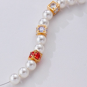 Macro-detail van vergulde vierkante kralen met zirkonia op een parelketting
