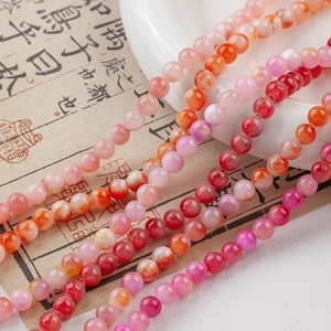 Detailed view of smooth pink and orange natural jade beads for DIY jewelry making