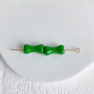 Détail de deux perles d'os vertes brillantes sur une tige dorée pour bijoux DIY