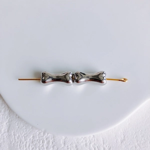 Détail de perles en forme d'os argentées sur tige dorée pour bijoux DIY créatifs