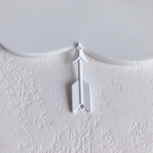 Macro view of a minimalist white arrow accessory with textured fletching for DIY jewelry